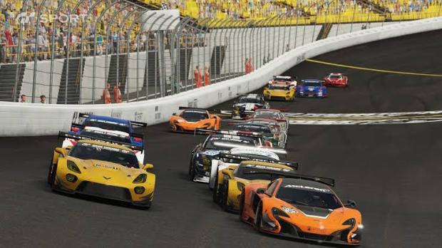 Gran Turismo Sport race footage shows an orange sports car leading a pack of cars through a banked turn beside a crowded grandstand.