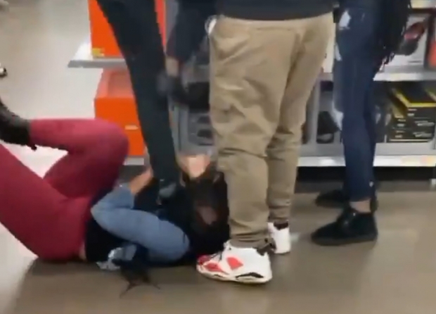 A woman steps on the head of another woman fighting for a PlayStation 5